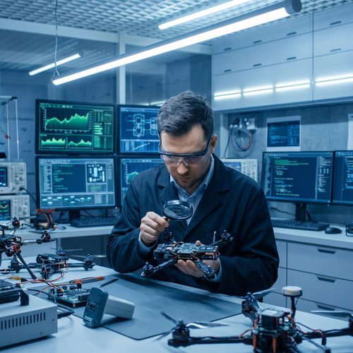 Technology researcher examining a drone component in a lab setting